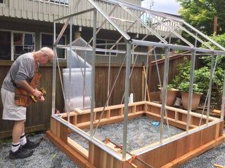 an older man is working on building a greenhouse