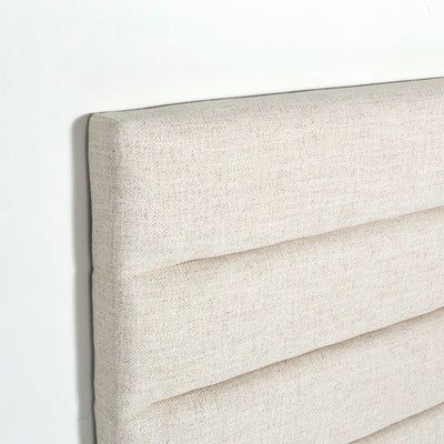 an upholstered headboard is shown against a white wall with no sheets on it