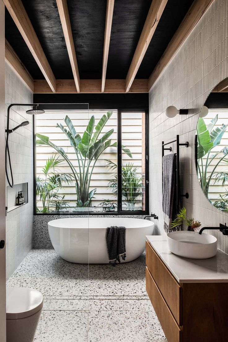 a bathroom with two sinks and a bathtub in the center, surrounded by large windows