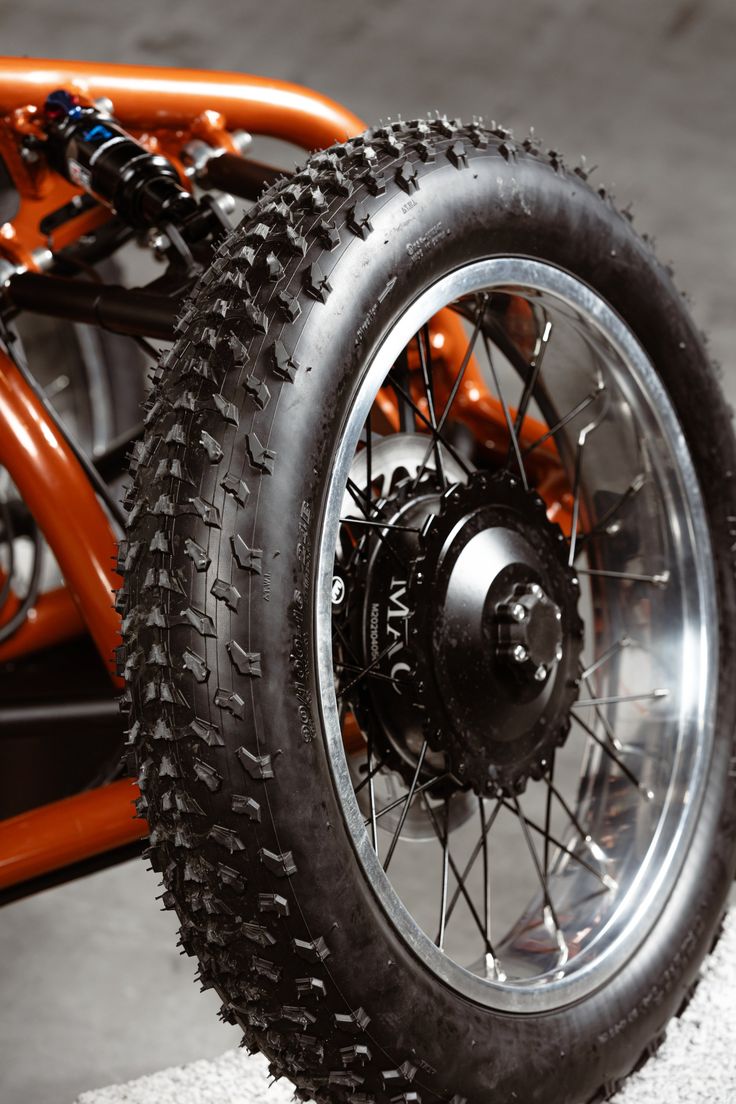 an orange and black motorcycle is parked on the cement with it's front tire