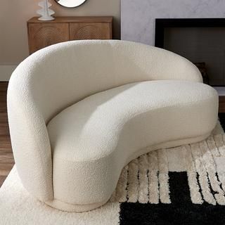 a white couch sitting on top of a rug in front of a fire place with a mirror above it