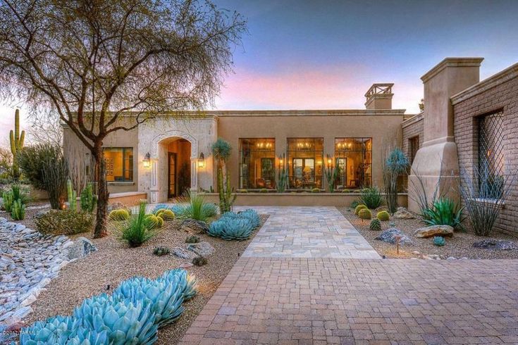 a home with cactus and succulents in the front yard at sunset or dawn