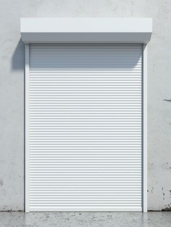 a closed up garage door on the side of a building with concrete flooring and white walls