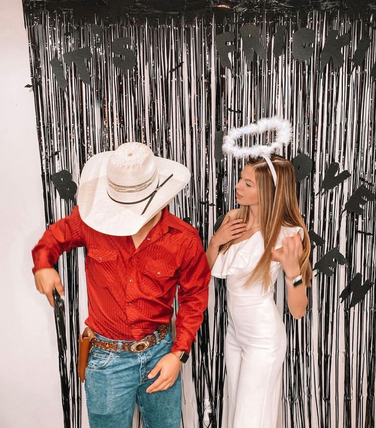 a man and woman dressed up as cowboy and cowgirl standing in front of a photo booth