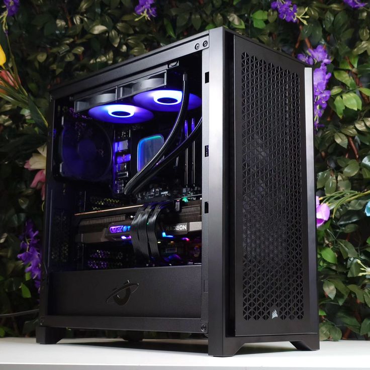 a black computer case sitting on top of a white table next to purple and yellow flowers