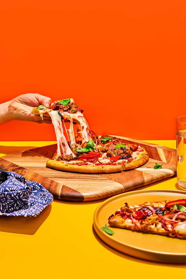 two pizzas are being served on wooden trays with orange walls in the background