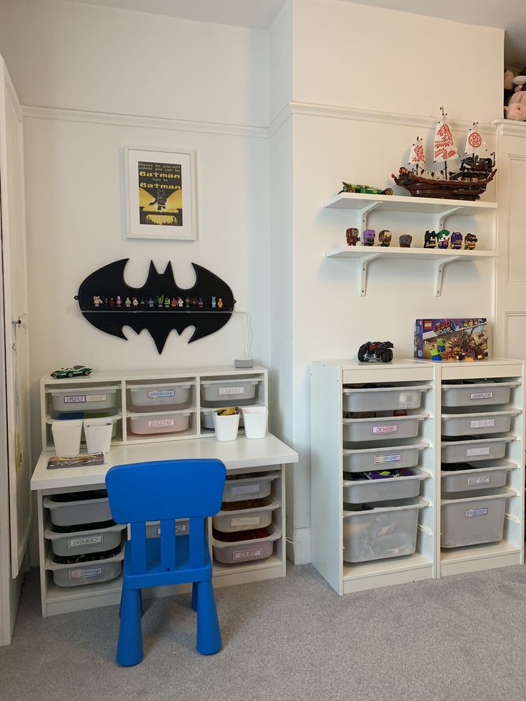 a child's room with toys and storage bins on the wall, including a batman decal