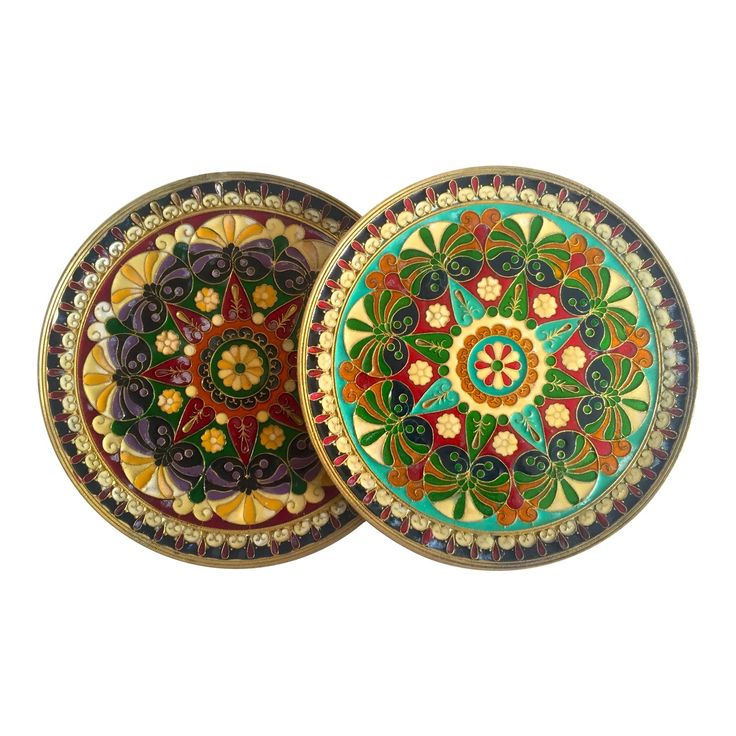 two colorful plates sitting next to each other on top of a white surface with an intricate design