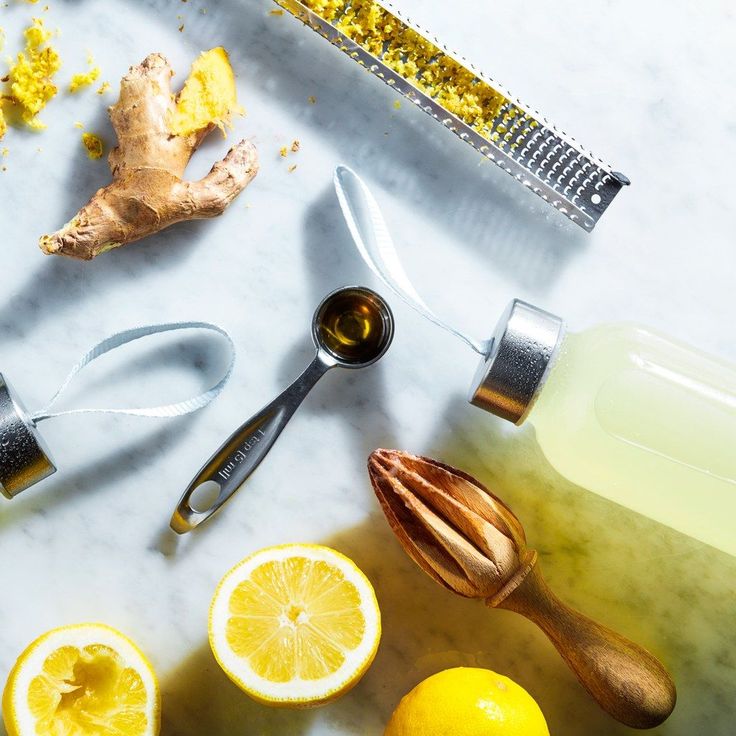 lemons, ginger and other ingredients on a white counter top with a grater