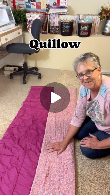 an older woman sitting on the floor next to a quilt