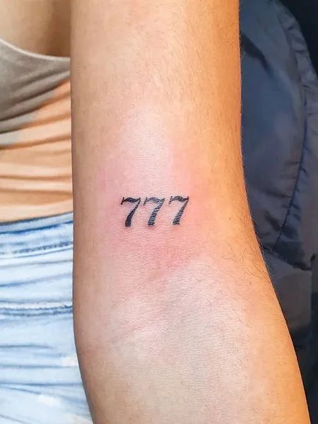 a woman's arm with a small tattoo that reads 777 on the side