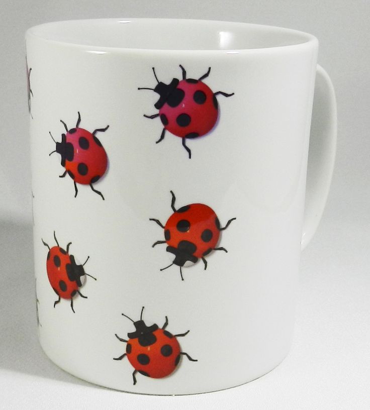 a coffee cup with ladybugs painted on the outside and inside, sitting on a white surface