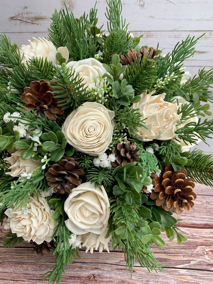 a bouquet of flowers with pine cones and greenery