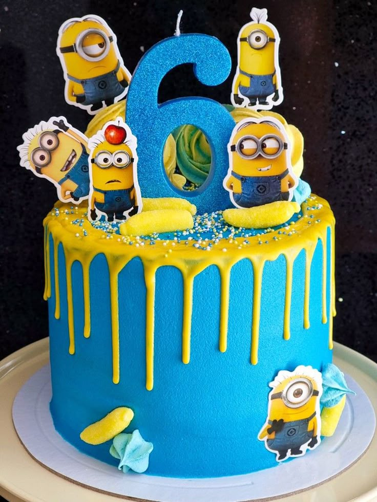 a blue and yellow birthday cake with minion figures on the top, number two