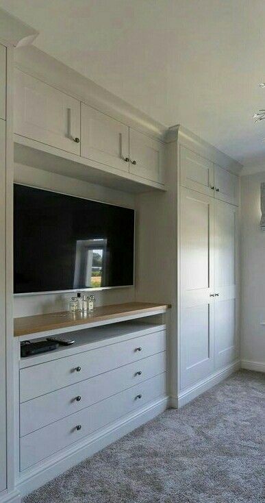 an empty room with white cabinets and a flat screen tv mounted to the side of it