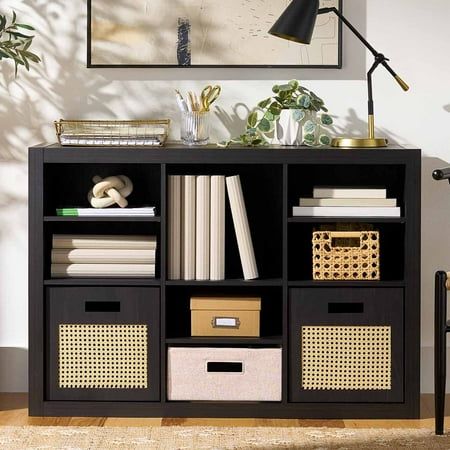 a black bookcase with baskets and books on it