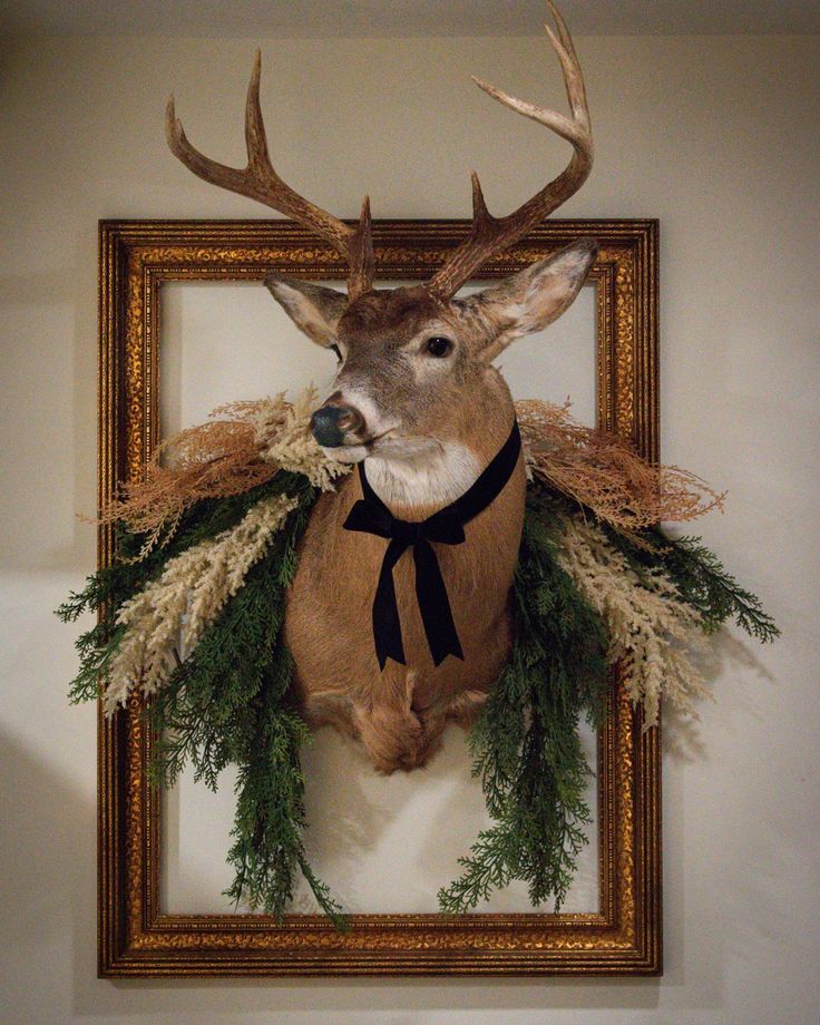 a deer's head mounted on the wall with grass and antlers around it