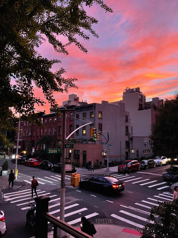 a city street filled with lots of traffic under a colorful sky