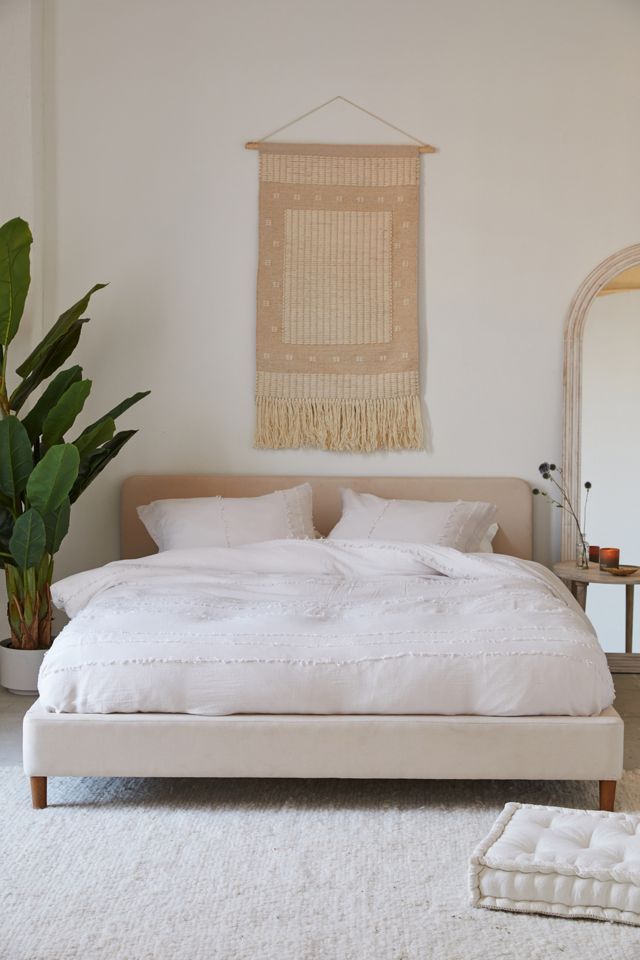 a white bed sitting in a bedroom next to a potted plant