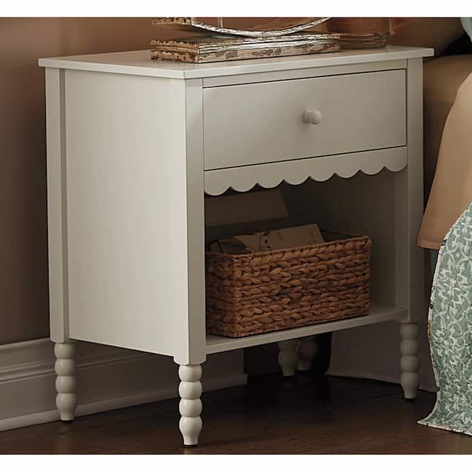 a white table with a basket on top of it next to a bed and nightstand