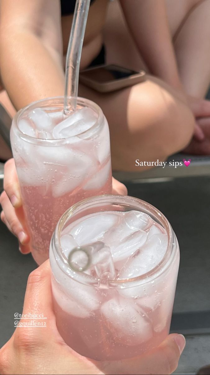 two people are holding glasses with ice in them