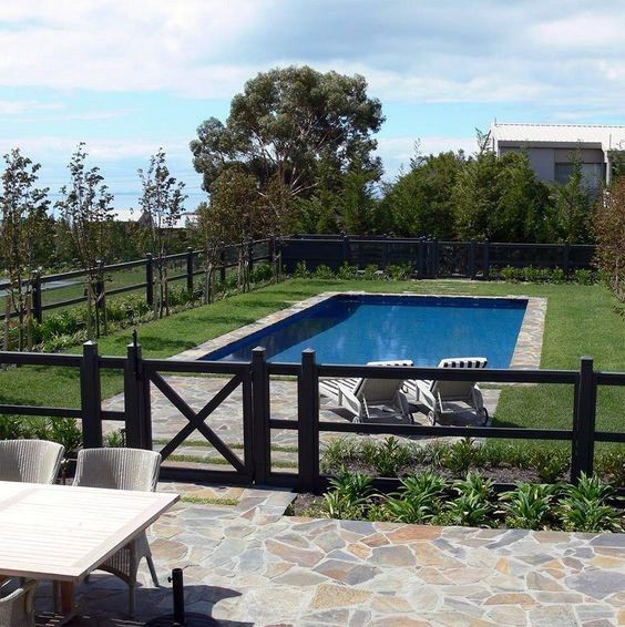 an empty swimming pool in the middle of a yard with chairs and tables around it