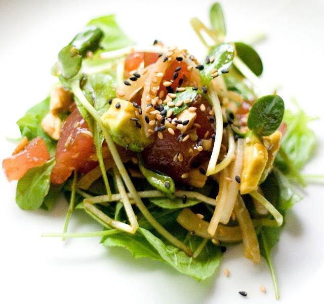 a salad with lettuce, tomato and sesame seeds on top is shown here