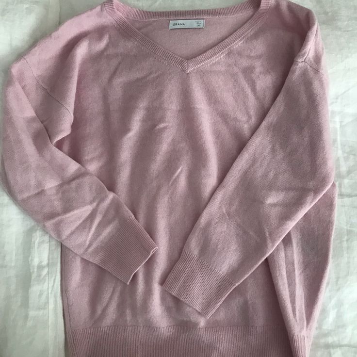 a pink sweater laying on top of a bed