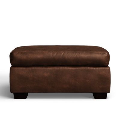 a brown leather footstool sitting on top of a white floor