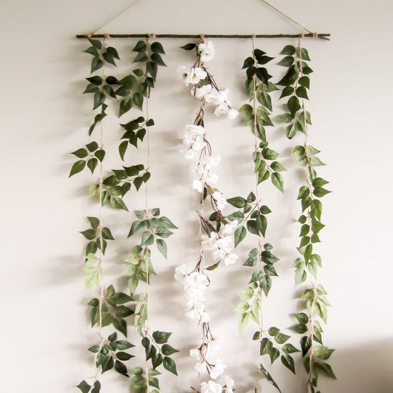 a wall hanging with white flowers and green leaves