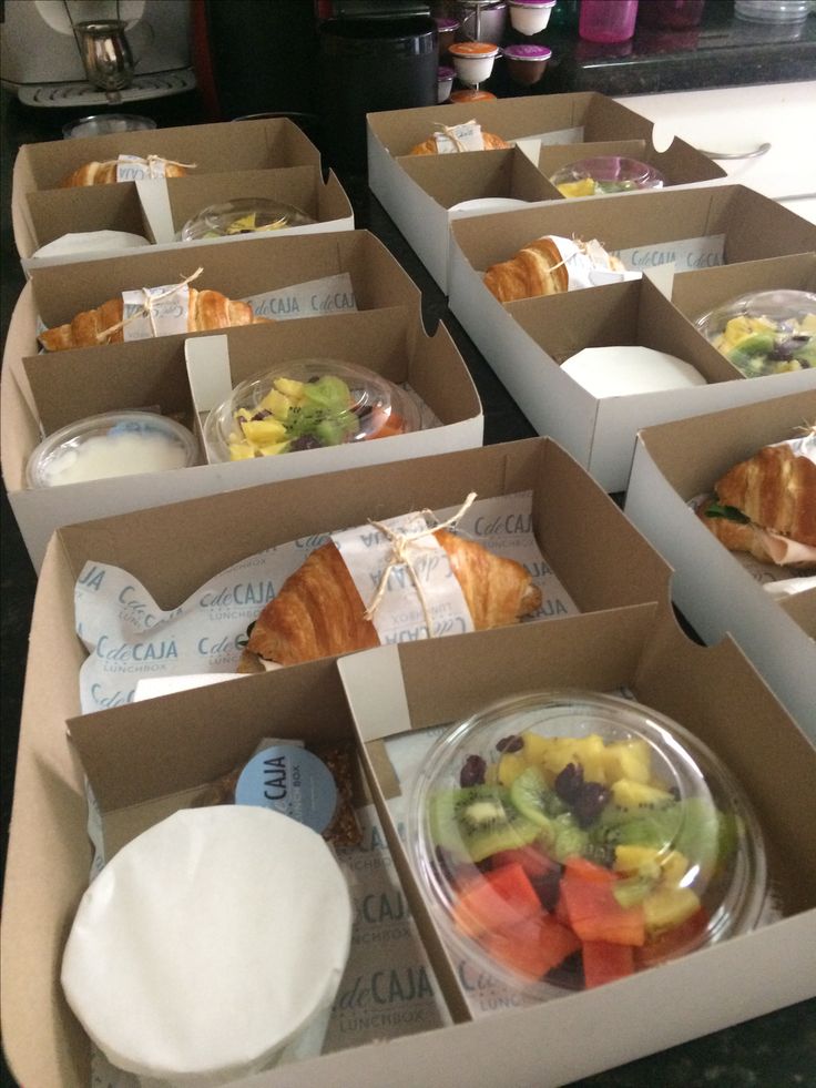 several boxes filled with food sitting on top of a counter next to plates and cups