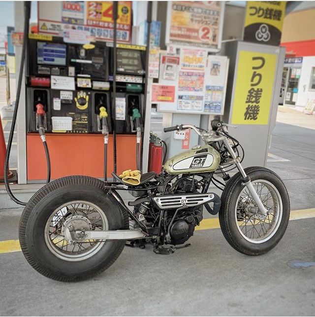 a motorcycle is parked in front of a gas station with no fuel at the pump