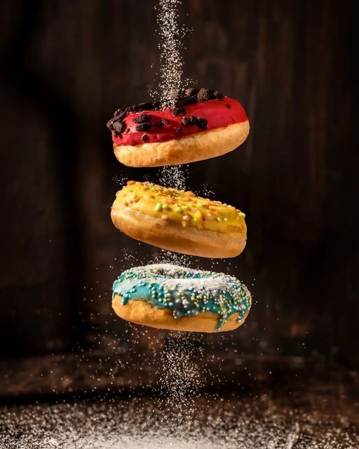 three donuts are falling into the air with sprinkles