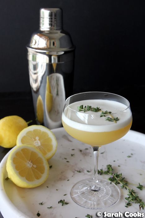 a drink in a glass next to lemons and a cocktail shaker