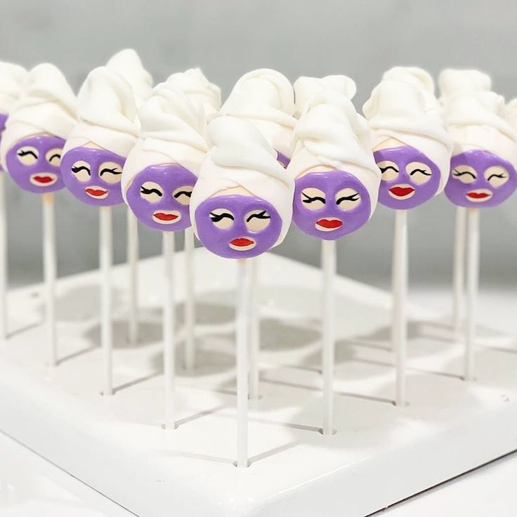 there are many purple and white marshmallows on sticks with faces painted on them