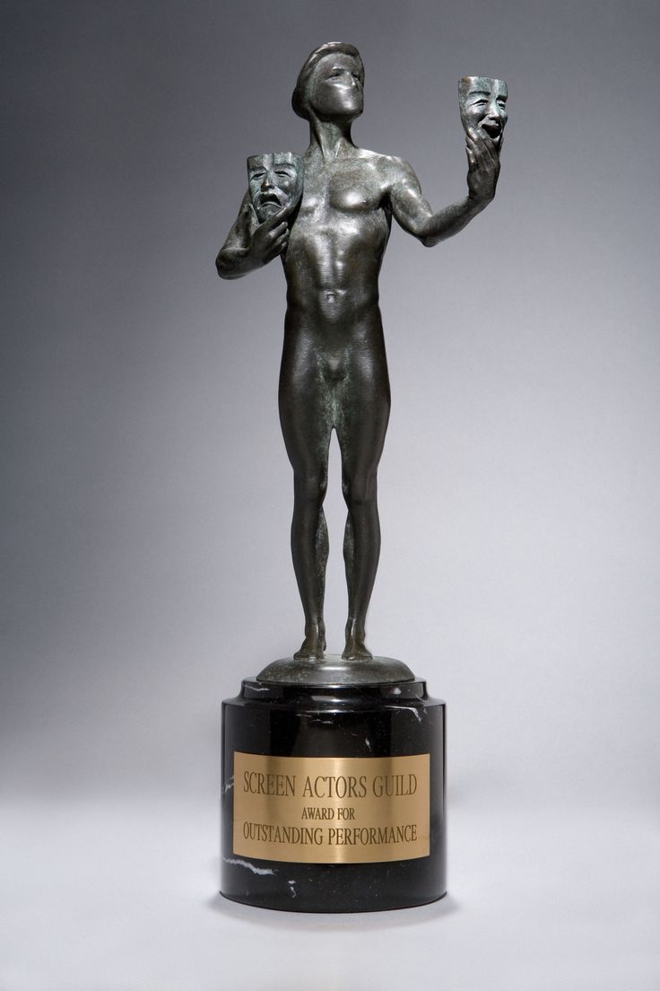 a bronze statue holding an award on top of a table