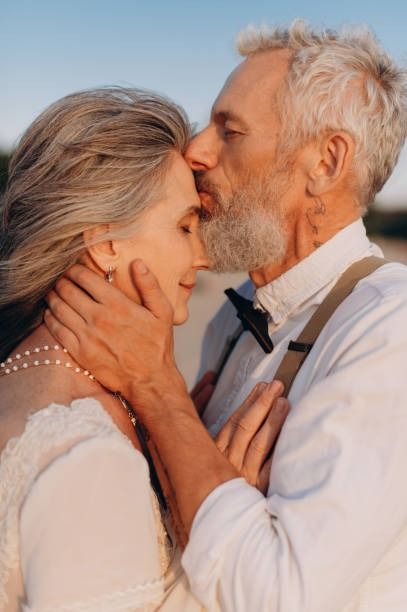 an older couple kissing each other on the beach