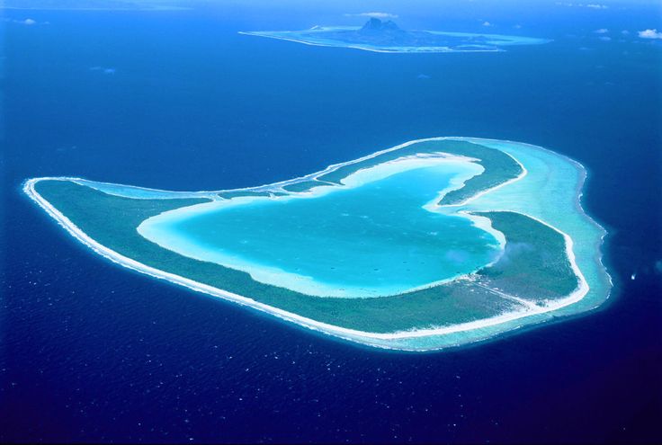 an island in the middle of the ocean with blue water and white sand on it