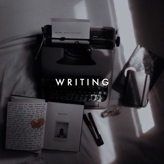 an old typewriter sitting on top of a bed next to a book and pen