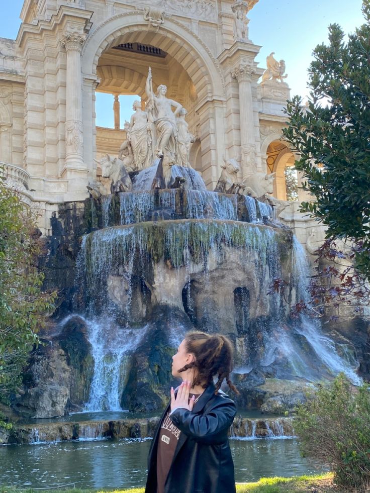 a woman standing in front of a water fountain