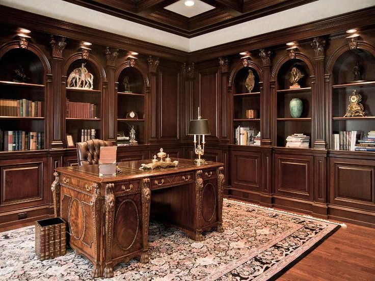 a large wooden desk sitting in the middle of a room with lots of bookshelves