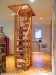 a wooden spiral staircase in the middle of a living room next to a man looking at it