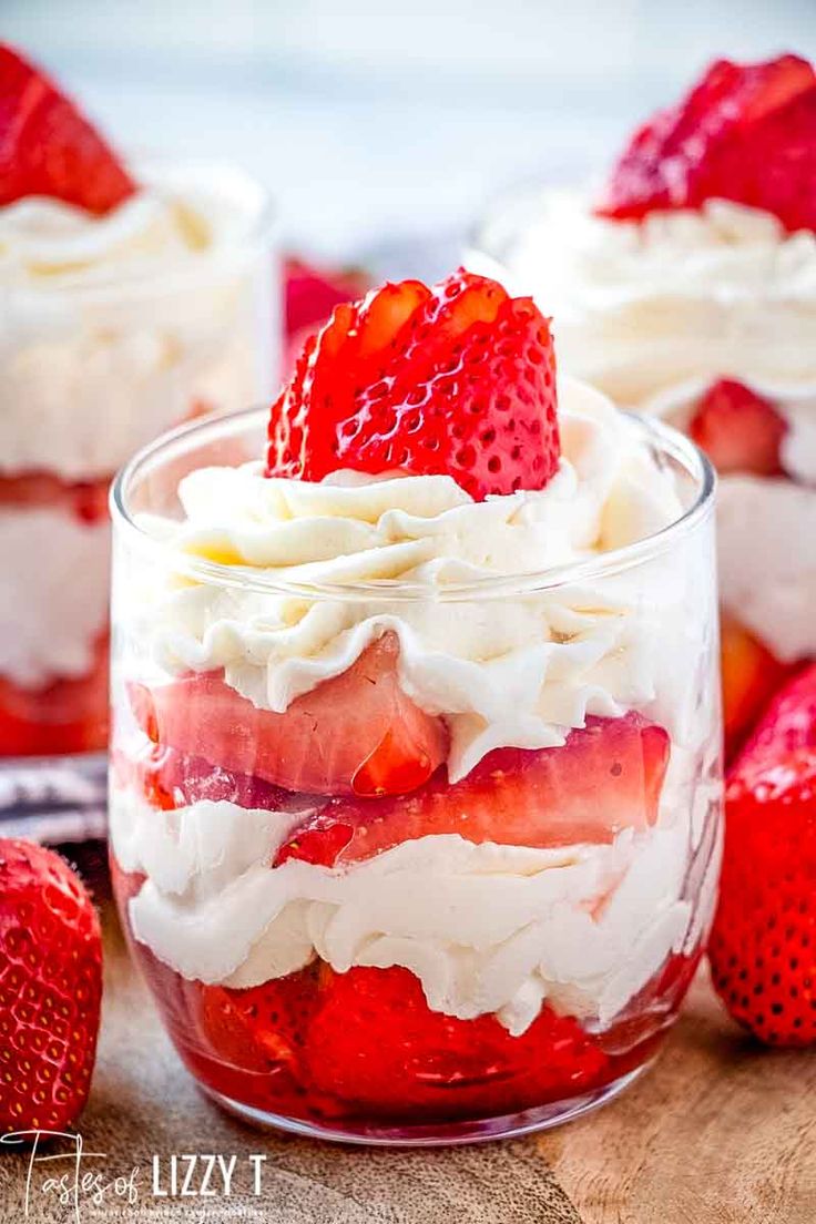 strawberry shortcake trifle in a glass dish with whipped cream and strawberries on the side