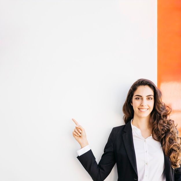 a woman standing next to a white wall with her hand up in the air and smiling