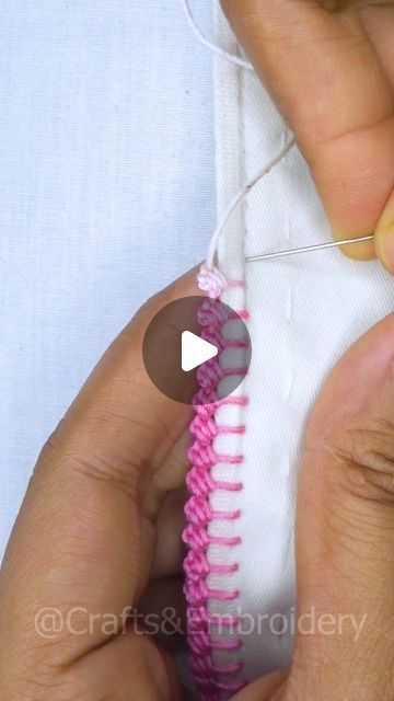 someone is stitching the end of a pink and white piece of fabric with scissors