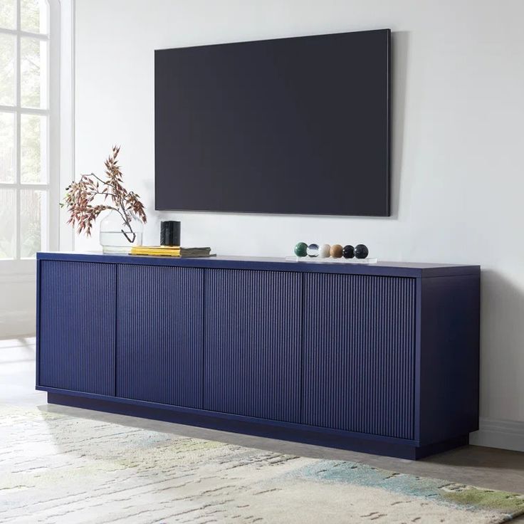 a large television mounted to the side of a blue cabinet in a room with white walls