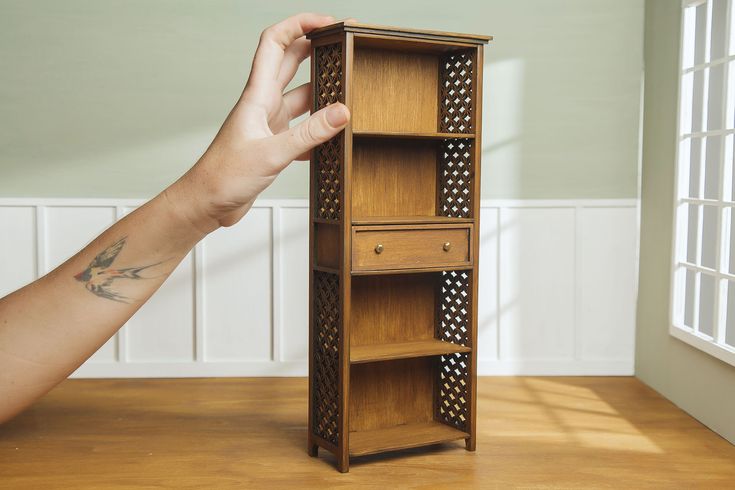 a person's hand is reaching into a wooden bookcase with polka dots on it