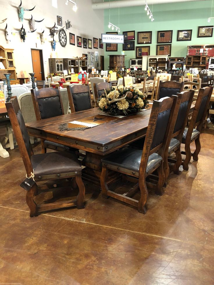 a large wooden table surrounded by chairs in a store