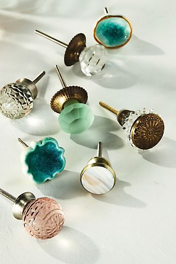 there are many different colored knobs on this white surface, including one for the door and one for the drawer