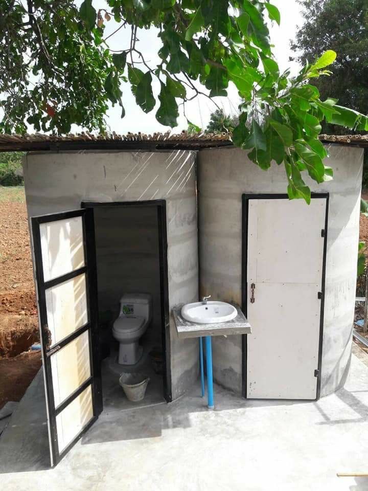 an outdoor toilet and sink in a small building with two doors open to the outside